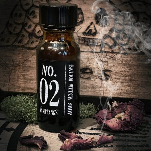 An Apothecary bottle of Vampfangs Fragance: No.2 Salem Witch Shop photographed in an actual Salem Witch Shop named Hex. A cracked, wooden board with an etched in skull. Smoking rose petals and some green moss complete the photo as accents.