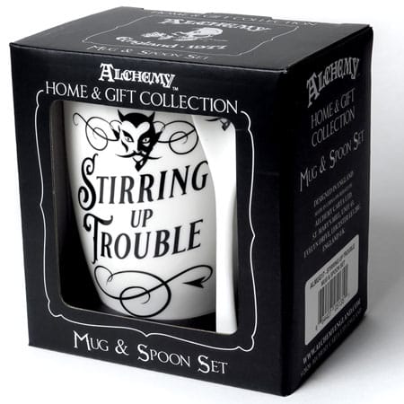 Open face box of the "Stirring Up Trouble" coffee mug from Alchemy of England's Home & Gift Collection. It is a white mug and spoon set with black print.