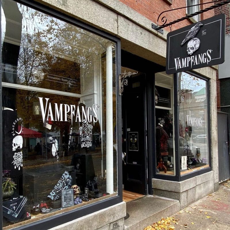 A picture of the storefront for the Vampfangs Salem location. It has black paint and a beautiful sign with a skull and a crow on it.