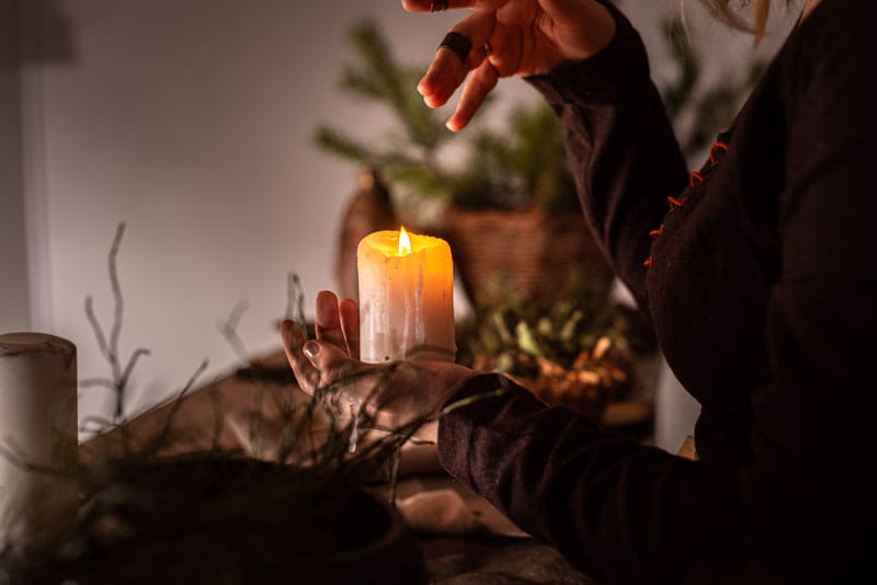 A lit candle held by a woman waving her hand over it.